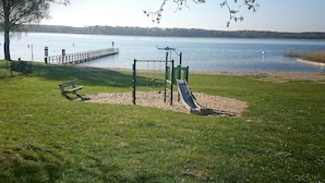 Un parque infantil con un tobogán y una estructura para escalar cerca de un lago.