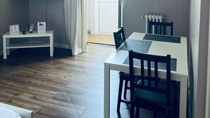 A modern living room with a flat-screen TV, a dining table with chairs, a white console table, and a large window with curtains. - Full house (Bari)