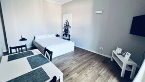 A modern hotel room with a large bed, a dining table, and a small seating area. - Full house (Bari)