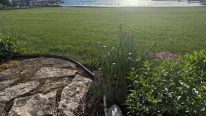 A grassy area with a stone pathway leading to a dock by the water.