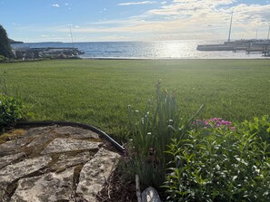 A grassy area with a stone pathway leading to a dock by the water.
