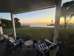 A covered patio with outdoor furniture, a small table, and hanging flower baskets. - Cozy Sister Bay Waterfront!
Ground level porch, lawn, pier, bay, garage parking (Sister Bay)