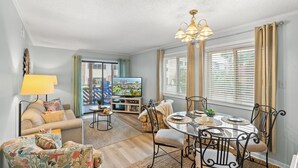 Een woonkamer met een bank, fauteuil, eettafel en televisie.