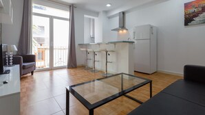 A modern kitchen with a glass-top table, bar stools, a refrigerator, and a large window with curtains. - El BALNEARIO Apartment by Cadiz4Rentals (Cádiz)