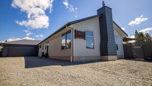 A single-story house with a gabled roof, a chimney, and a garage. - Remarkable  Rhoboro Retreat (Twizel)