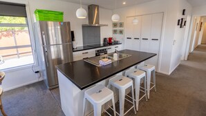 A modern kitchen with a central island, stainless steel appliances, and white cabinetry. - Remarkable  Rhoboro Retreat (Twizel)