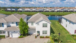 A residential area with white houses, a lake, and a well-maintained lawn.