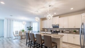 A modern kitchen with white cabinets, a granite countertop, and a central island with bar stools.