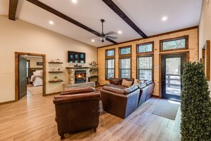 Una sala de estar acogedora con chimenea, sofás de cuero y ventanas grandes.