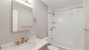 A modern bathroom with a white sink, vanity, and toilet, a glass shower enclosure, and a large mirror with lights. - 3 Bed 2 Bath Tourist House near Kendall Square (Cambridge)