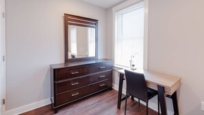 A bedroom with a dark wooden dresser, a mirror, a desk with a chair, and a window with blinds. - 3 Bed 2 Bath Tourist House near Kendall Square (Cambridge)