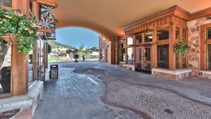 A hotel entrance with a stone facade, wooden doors, and a paved walkway leading to the lobby. - Sundial studio in the heart of Canyons Village, private patio, outdoor pool, walk to hiking & biking (Park City)