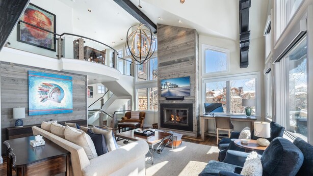 A spacious living room with a fireplace, comfortable seating, and a large window offering a view of the outdoors. - Deer Valley luxury mountainside escape, outdoor seating, private hot tub, walk to hiking trails (Park City)