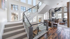 A spacious interior with a grand staircase, large windows, and a modern kitchen. - Deer Valley luxury mountainside escape, outdoor seating, private hot tub, walk to hiking trails (Park City)