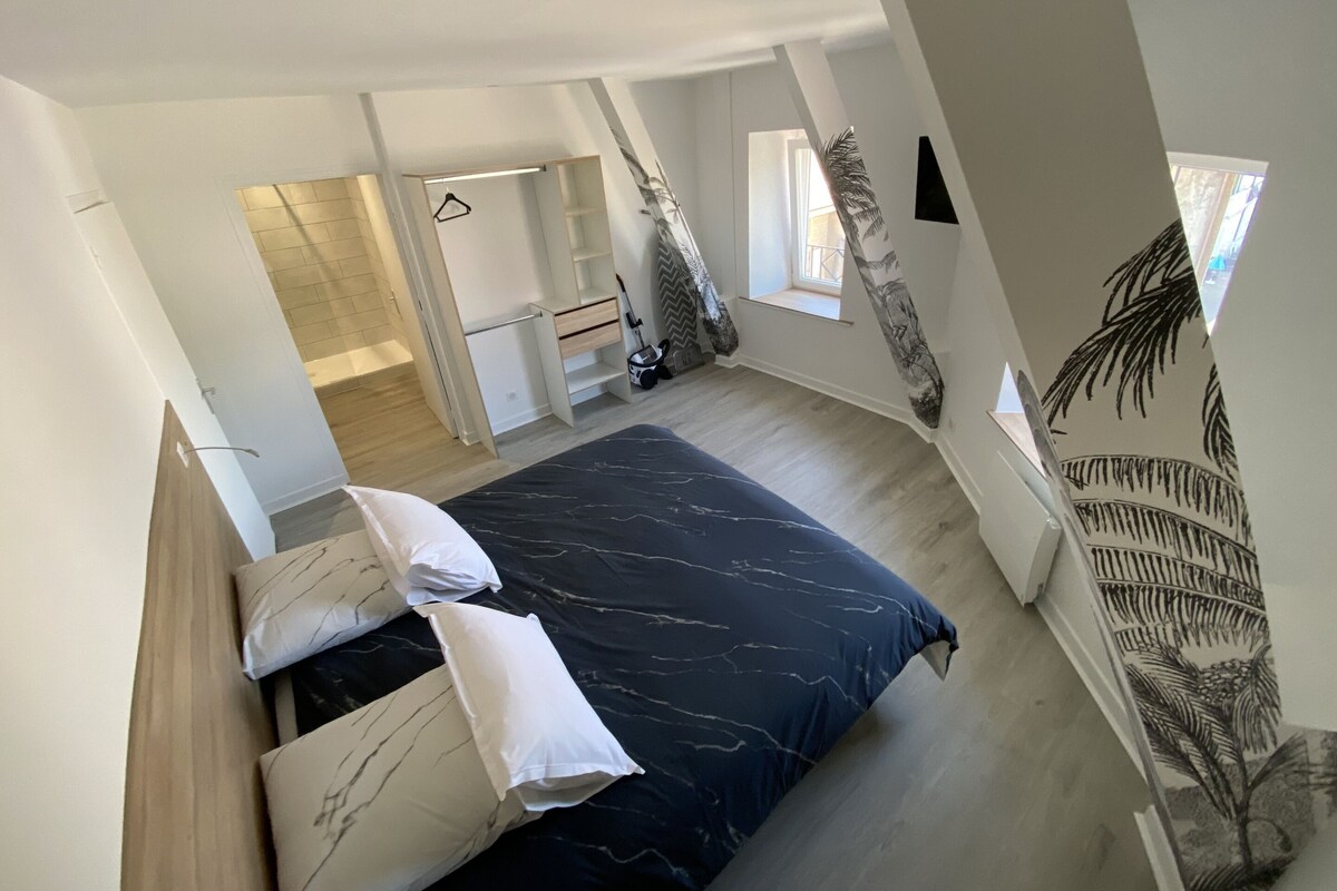 A modern bedroom with a bed, a wardrobe, and a small window.