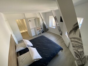 A modern bedroom with a bed, a wardrobe, and a small window. - Résidence Gaby & Tom (Contrexéville)