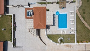 Ein Luftbild eines Wohnhauses mit Schwimmbad, Sitzbereich im Freien und gepflegtem Rasen.