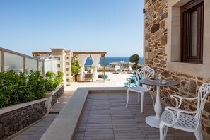 A terrace with a stone wall, white chairs, a table, and a view of the sea. - Agapi Villa II, a Seaside Retreat with Pool & BBQ, Walking distance to beach (Rethymno)