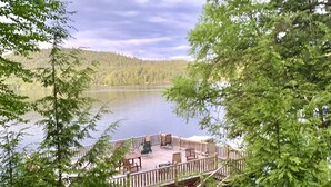 Terraza junto al lago con mobiliario exterior, rodeada de un bosque denso.