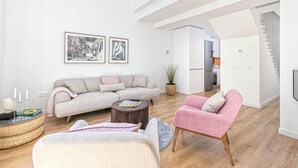 Una sala de estar moderna con un sofá, sillones, una mesita de centro y obras de arte en la pared.