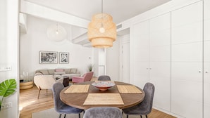 Un comedor moderno con una mesa redonda, sillas tapizadas en gris, individuales tejidos y un cuenco decorativo como centro de mesa.