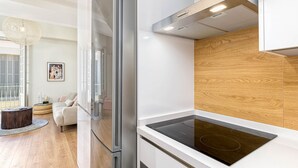 Una cocina moderna con estufa integrada, refrigerador y paneles de madera en la pared.