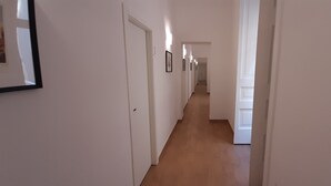 Een lange, smalle gang met witte muren en houten vloer.