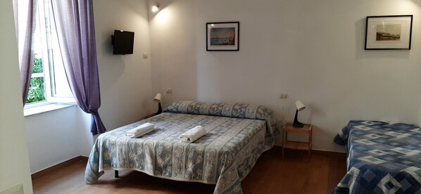A bedroom with a bed, a bedside table, a lamp, and a window with curtains.