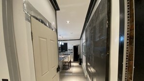 A narrow hallway with a kitchen area at the end, featuring a countertop and chairs. - The Blackberry Tree House (Camden)