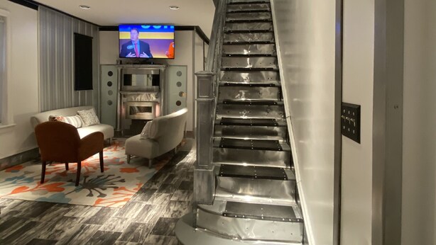 A modern interior with a curved staircase, a flat-screen TV, and a seating area with a patterned rug. - The Blackberry Tree House (Camden)