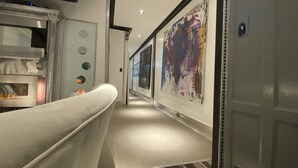 A hallway with a modern design, featuring a large abstract painting on the wall, a television mounted on the wall, and a metallic structure with a glass door. - The Blackberry Tree House (Camden)