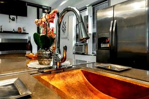 A modern kitchen with a stainless steel sink, a faucet, and a refrigerator. - The Blackberry Tree House (Camden)