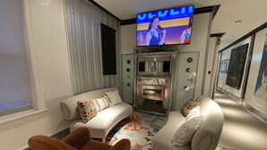 A modern living room with a flat-screen TV mounted on the wall, a fireplace, and two sofas with decorative pillows. - The Blackberry Tree House (Camden)
