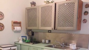 A compact kitchen with a sink, cabinets, and a small dining table. - Casa Vacanze The Family (Campania)