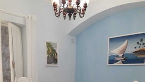 A bedroom with a bed, a chair, a lamp, and a painting on the wall. - Casa Vacanze The Family (Campania)