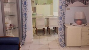 A room with a bed, a desk, and a chair. There is a cabinet with a lamp on top. - Casa Vacanze The Family (Campania)