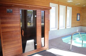 Un'area benessere con una cabina in legno, una piscina e una scaletta metallica.