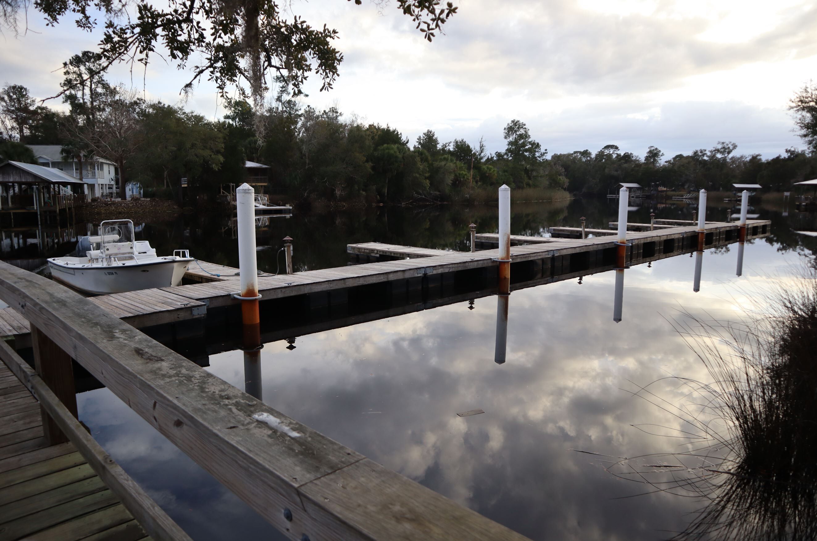 A wooden dock extending into calm water with a boat docked at the end.
