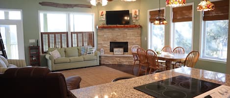A modern kitchen with a granite countertop, built-in stove, and dining area with wooden chairs and a table.