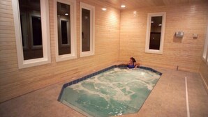 Un cuarto de spa con un jacuzzi, paredes de madera y ventanas amplias.