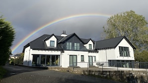 A modern two-story house with a large garage and a covered driveway. - Taransay House (Portree)