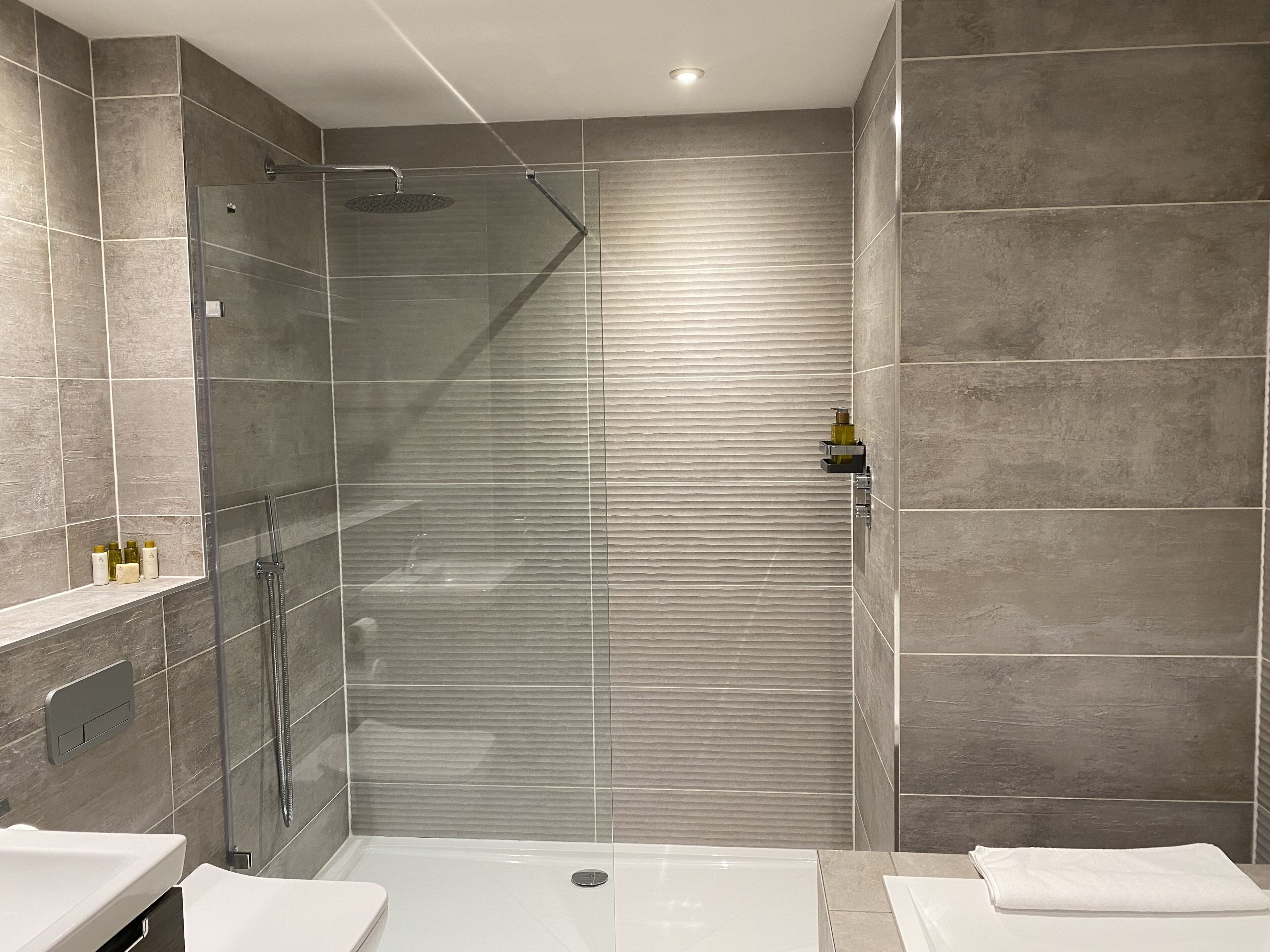 A modern bathroom with a glass-enclosed shower, a vanity with a sink, and a toilet.
