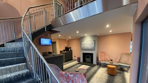 A modern interior with a staircase, a fireplace, and seating areas. - Taransay House (Portree)