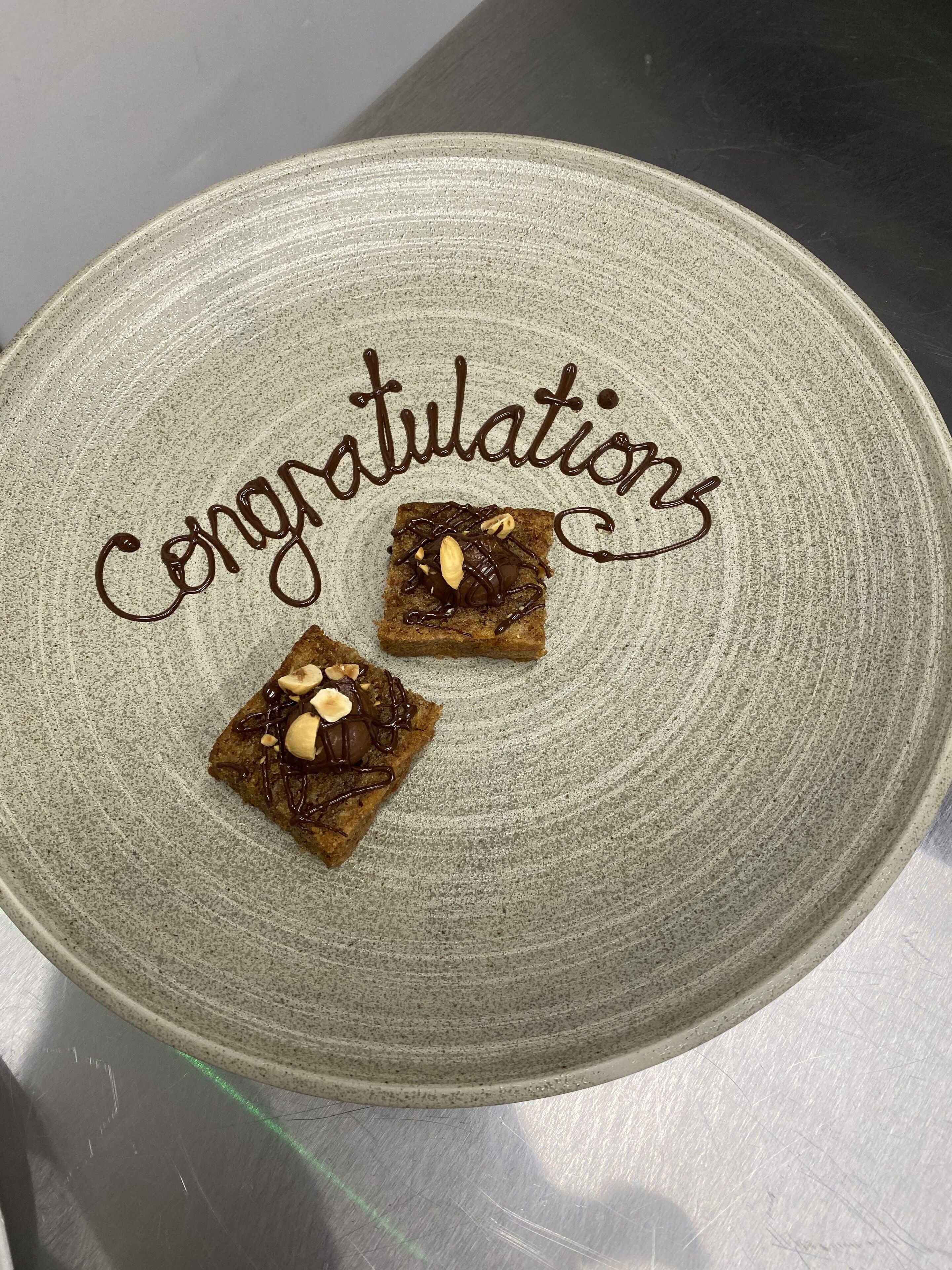 A plate with two brownies and the word "Congratulations" written on it.