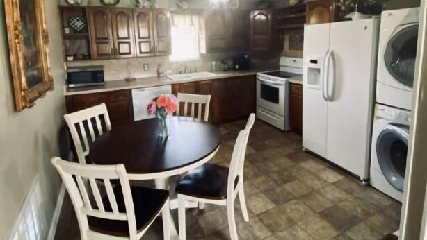 Une cuisine compacte comprenant une table à manger, des chaises, un réfrigérateur, un lave-linge et des placards en bois.