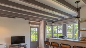 A kitchen with a bar area, large windows, and a television. - L'Atelier de La Maison Saint Léonard | pretty shared garden honfleur center (Honfleur)