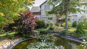 A pond with lily pads surrounded by lush greenery and a house in the background. - L'Atelier de La Maison Saint Léonard | pretty shared garden honfleur center (Honfleur)