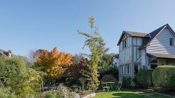 Stroll through the beautifully maintained garden, leading to a traditional home with a gabled roof.
