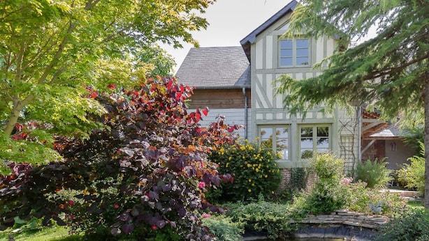 Une maison traditionnelle à colombages, dotée d’un jardin bien entretenu et d’un petit étang.