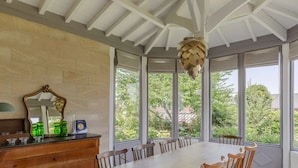 Un coin repas comprenant une longue table, des chaises, un buffet en bois avec des bocaux en verre et un miroir.